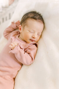Newborn baby in a pink romper sleeping
