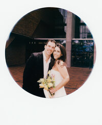 Polaroid photo of two brides sitting closely together and holding lush, textured wedding bouquets — a tender film detail from a wedding made by a film wedding photographer.