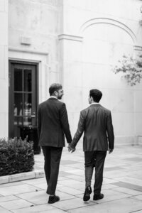 black and white image grooms holding hands