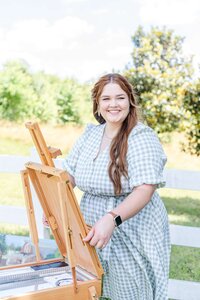 Elyse Stokes setting up her easel at a wedding venue, preparing with joy to create a live wedding painting during the ceremony and reception