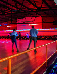 people rollerskating at an indoor rink with red lights