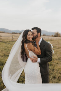 bride and groom embrace near greenery