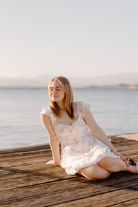 High school grad sitting on a dock looking away at Lake Pleasant Marina