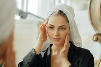 Woman lookin in the mirror touching her smooth skin