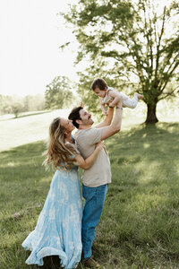 Family Photographer, mom and dad each holding up one child into the air having fun together