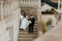 Bride and groom holding hands walking down steps at Chateau de Lis in Oregon City, Oregon