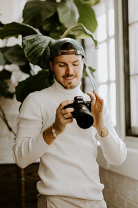 Clément, casquette sur la tête, vidéaste à the soulmate duo, examine l'écran de son appareil photo, concentré sur les réglages.