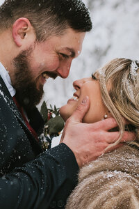 couple smiling up at each other in a wintery setting during their winter alaska elopement
