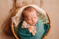Newborn photographer wrapped baby boy in a blue wrap in cleveland ohio