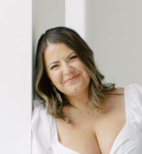 A woman smiling holding a camera.