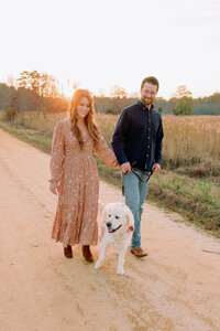 A couple holding hands and walking with their dog 