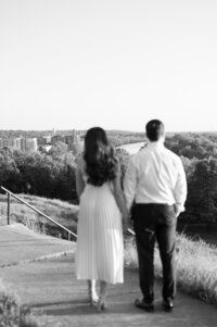 A couple holding hands and walking along a path in a grassy area