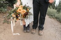 image of a bride and groom's shoes. Bride holding a bouqet.