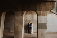 Newlyweds pose under stone archway