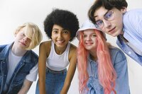 A group of young people with diverse genders, skin colors, and hair colors and textures stands together smiling toward the camera. They are all wearing white and denim outfits, in a variety of cominations.