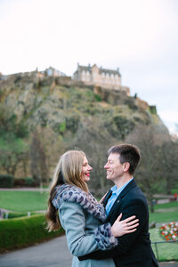 engaged couple smiles in front of castle