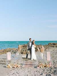 A Couple poses in the aisle with the beach behind them.