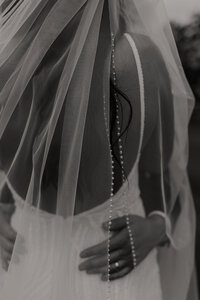 grooms wedding band through the brides veil detail photo