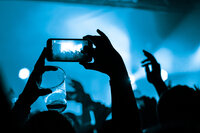holding up a phone to video record a concert