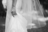 Black and white wedding photo of bride holding her dress.