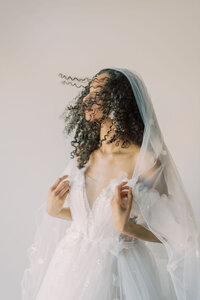 Fashion-forward bridal portrait of a black woman with her hair blowing and a veil