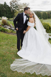 A bride and groom in a grass area posing for a photo