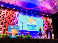 Woman on a colorful stage at a conference giving a speech