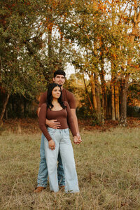 Couple holding hands in a golden farm field at sunset during a couples session in Aiken SC.
