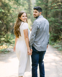This image depicts a bride holding her groom's hand as they navigate through rocky terrain at the Peyto Lake viewpoint in Banff National Park. The couple’s journey through the rugged landscape symbolizes their commitment to walk through life together, set against the stunning backdrop of the lake's vibrant turquoise waters.