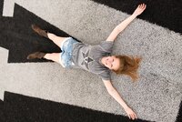 Vanderbilt college grad laying on the V of the football field