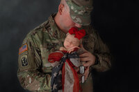 military dad holding baby girl in flag scarf with dog tags