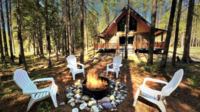 A fire pit and chairs  sit out front of a rustic cabin in the woods outside Glacier National Park.