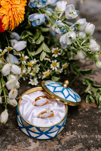 A round ring box holding engagement and wedding rings placed among flowers in Calgary, Alberta