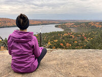 Tarzan sits on a cliff overlooking a beautiful forest that is a mix of late autumn colours