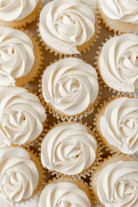 cupcakes decorated with white frosting in a rose design