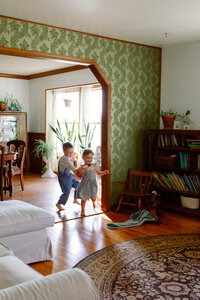 brother and sister run through house playfully during immersive morning family session in wentzville missouri