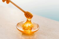 Honey in a dish with a honeycomb stirrer to promote honey as a main ingredient in Berry and Balm soaps