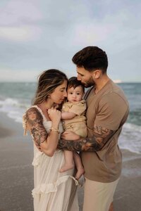 parents holding their baby in a beach area and very intimate moment