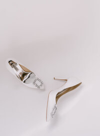 The groom is fastening the bride's shoe while sitting on the sofa