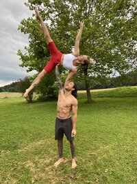 partner acro yoga man holds woman up in star shape