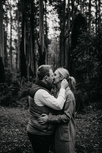 black and white image of engaged couple sharing a kiss