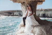 Couple seated at Cape Greco Sea Caves overlooking the crystal clear waters