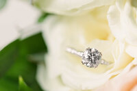 Close up of an engagement ring sitting on a flower