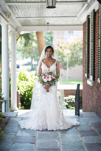 black charlotte bride in veil and flower bouquet looking straight into the camera