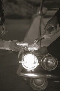 bride and groom pouring champagne with vintage car in background