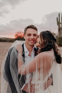 Bride snuggles with groom during sunset photos in the desert