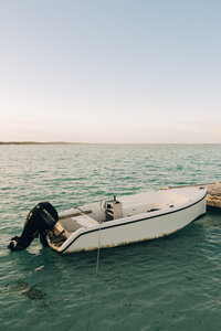 A small dingy boat floats while on anchor in the flats