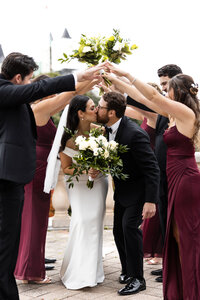 Wedding couple kissing with their friends cheering them on outside of Chateau Laurier located at Ottawa, Ontario