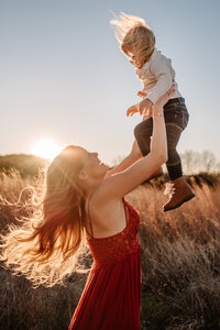 woman holding child up in the air