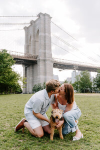 Couple kissing with dog in Brooklyn Bridge Park.